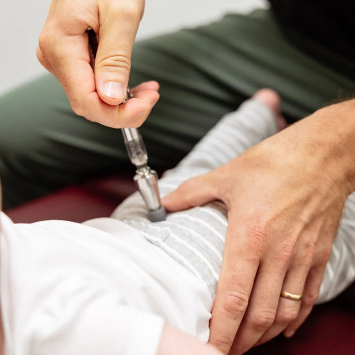 A lifestyle image showing the Activator I being used on a pediatric patient, demonstrating the mild thrust gentle enough for pediatric and geriatric care.