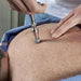 A lifestyle shot of the Activator I chiropractic instrument during a spinal adjustment, showcasing its reliable use in professional clinical practice.