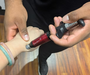 A lifestyle shot of the ACTIVATOR IV instrument during a wrist treatment, highlighting its ergonomic handles and predetermined force settings.