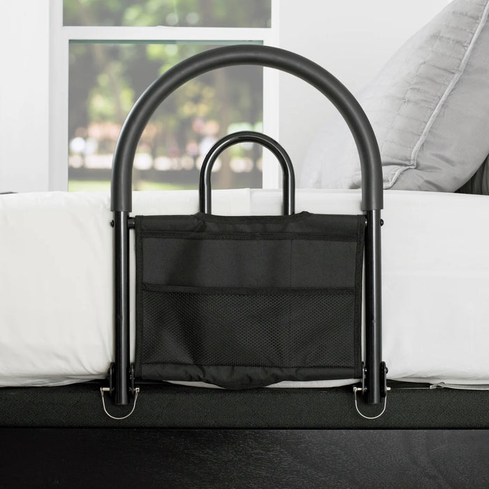 Bed assist rail model 5000 main product image showing the black metal safety rail with attached storage pouch attached to a white bed, from Therapy Supply