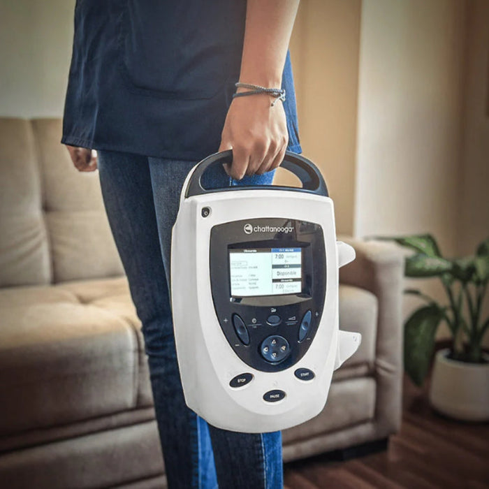 A person carrying the lightweight Intelect Transport 2 Ultrasound unit indoors, highlighting its convenient handle and compact size for clinical mobility.