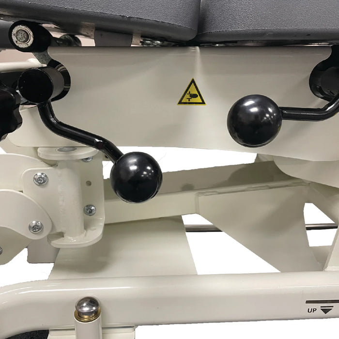 Close-up of black adjustment levers and hardware underneath a chiropractic treatment table