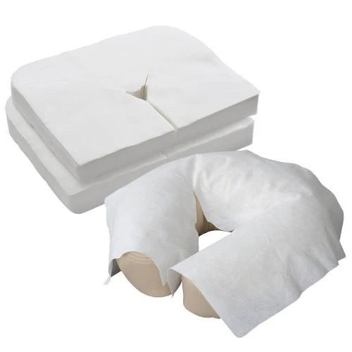 Stack of white luxurious disposable face cradle covers for massage tables shown with a face rest cushion