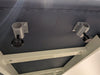 Underside view of a massage table showing two aluminum face cradle bracket mounts with thumbscrews