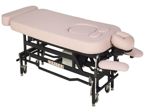 Angled view of the MT Electric Hi-Lo Massage Table with the prenatal option, featuring a sturdy black metal frame, pink upholstery, and specialized cutouts for belly and breast comfort during professional therapy.