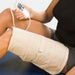 A person using the Theratherm heating pad on their leg, illustrating its versatility for use on the back, shoulder, wrist, stomach, knee, or foot.